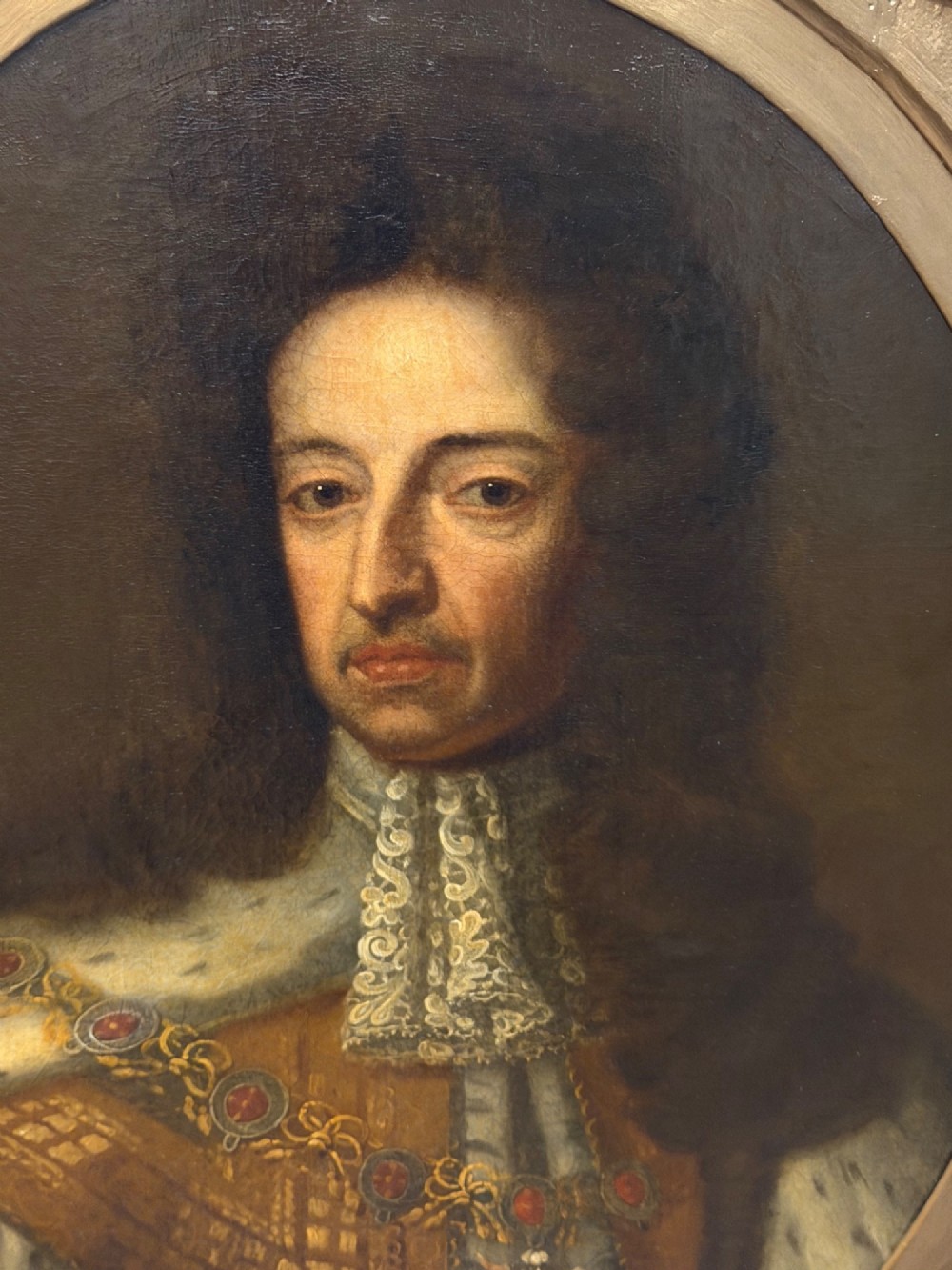 An 18th-century oil painting depicting King William III in a curled wig and ermine cloak, set within an oval aperture inside an ornate rectangular gold carved frame. View VII