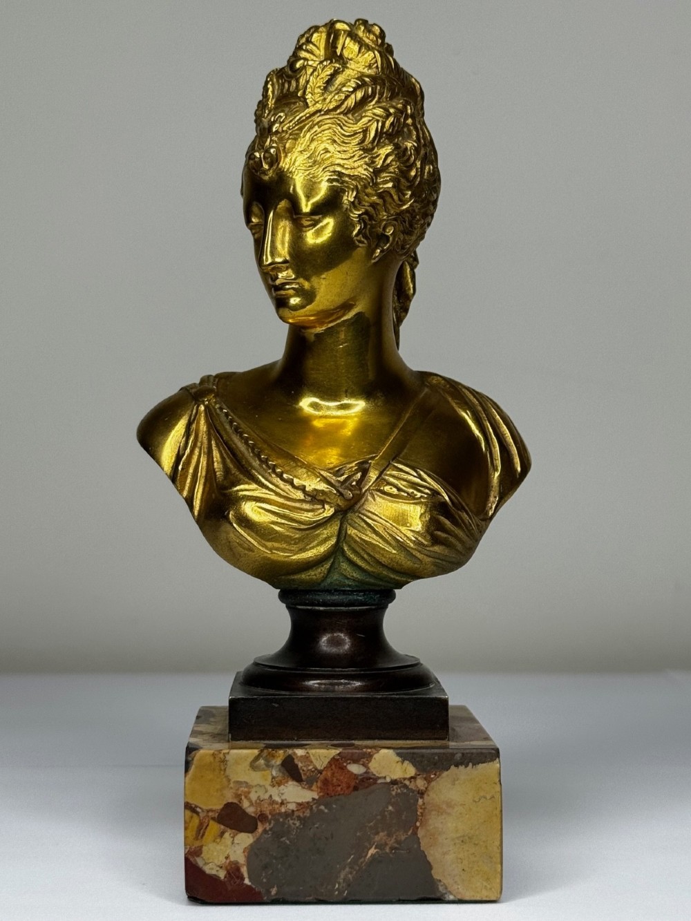 A 19th-century gilt bronze bust portrait of Diana de Poitiers featuring an ornate hairstyle and classical drapery, mounted on a dark socle and square variegated marble base. View II