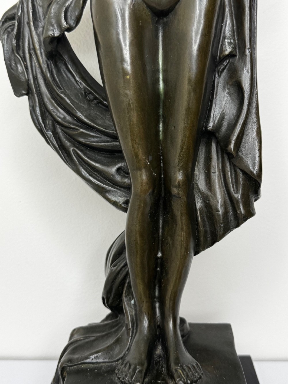 A dark brown patinated French bronze sculpture depicting a standing female nude draped in flowing fabric, mounted on a dark marble base. View V