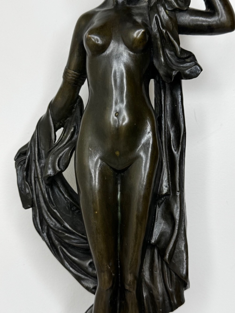 A dark brown patinated French bronze sculpture depicting a standing female nude draped in flowing fabric, mounted on a dark marble base. View VI