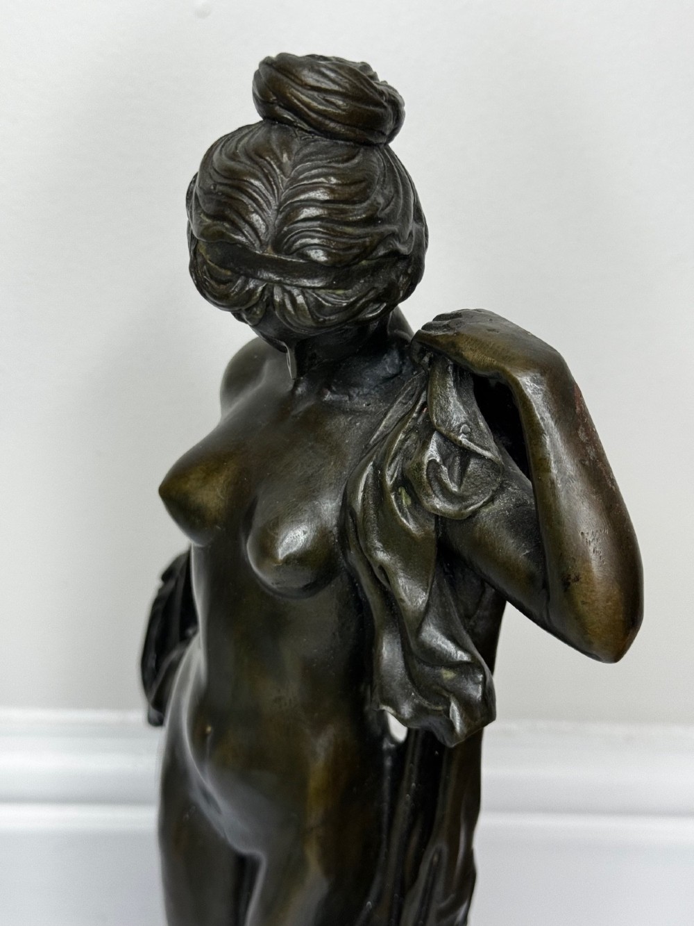 A dark brown patinated French bronze sculpture depicting a standing female nude draped in flowing fabric, mounted on a dark marble base. View VII
