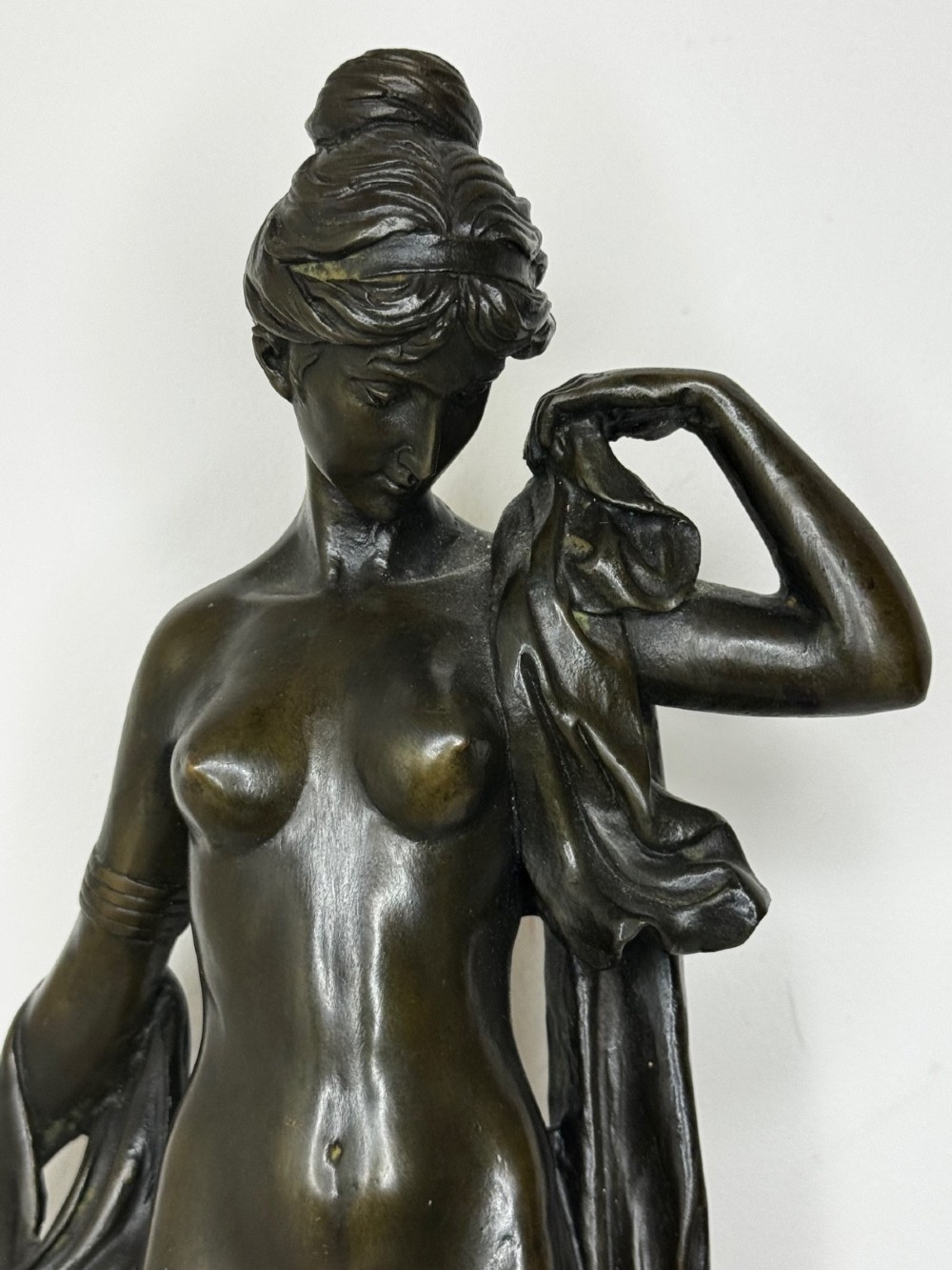 A dark brown patinated French bronze sculpture depicting a standing female nude draped in flowing fabric, mounted on a dark marble base. View X