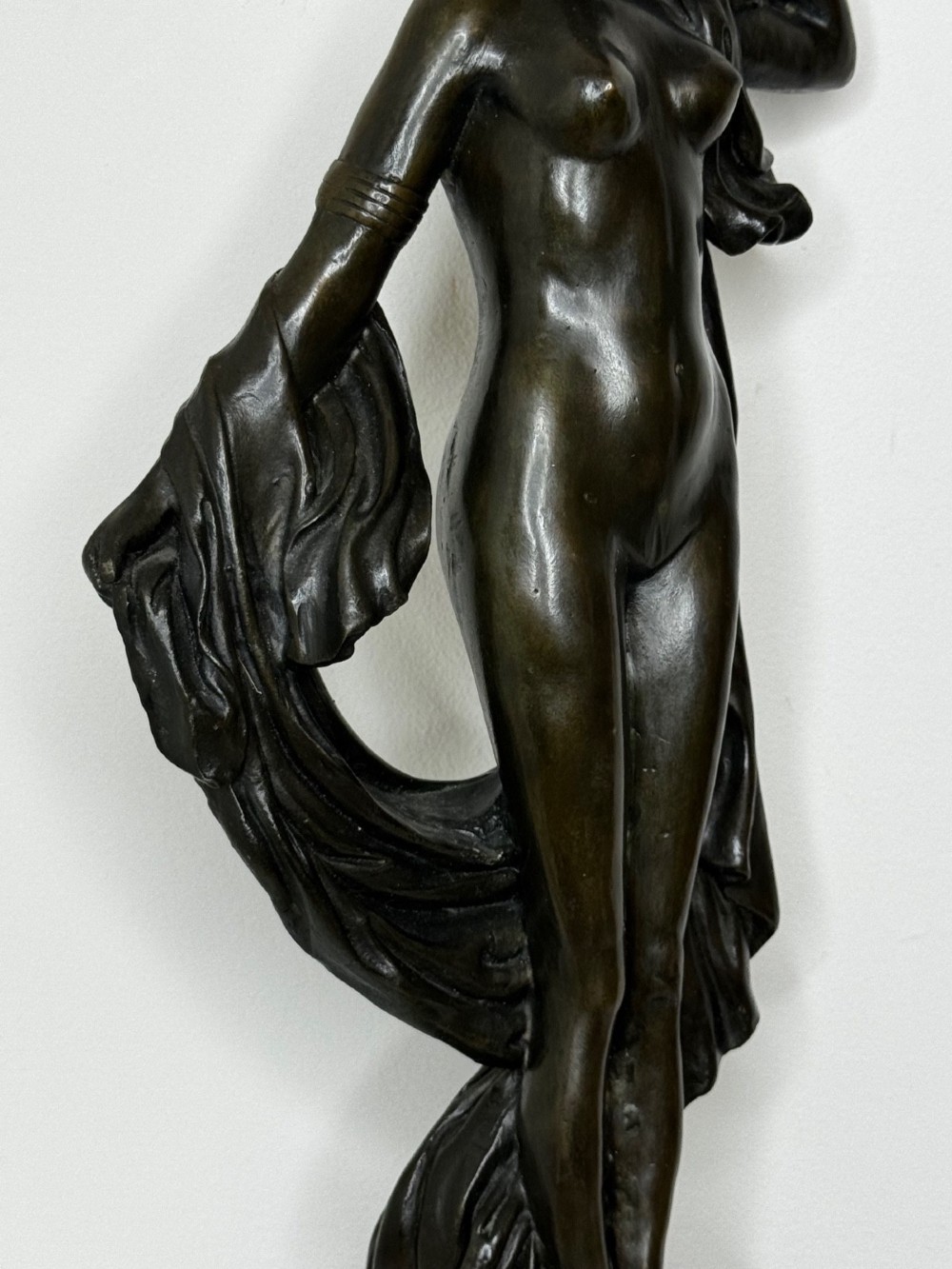 A dark brown patinated French bronze sculpture depicting a standing female nude draped in flowing fabric, mounted on a dark marble base. View XII