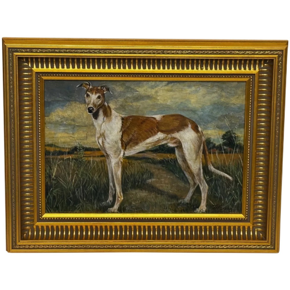An antique Edwardian oil painting depicting a tan and white lurcher dog in a landscape, set within an ornate gilded frame.