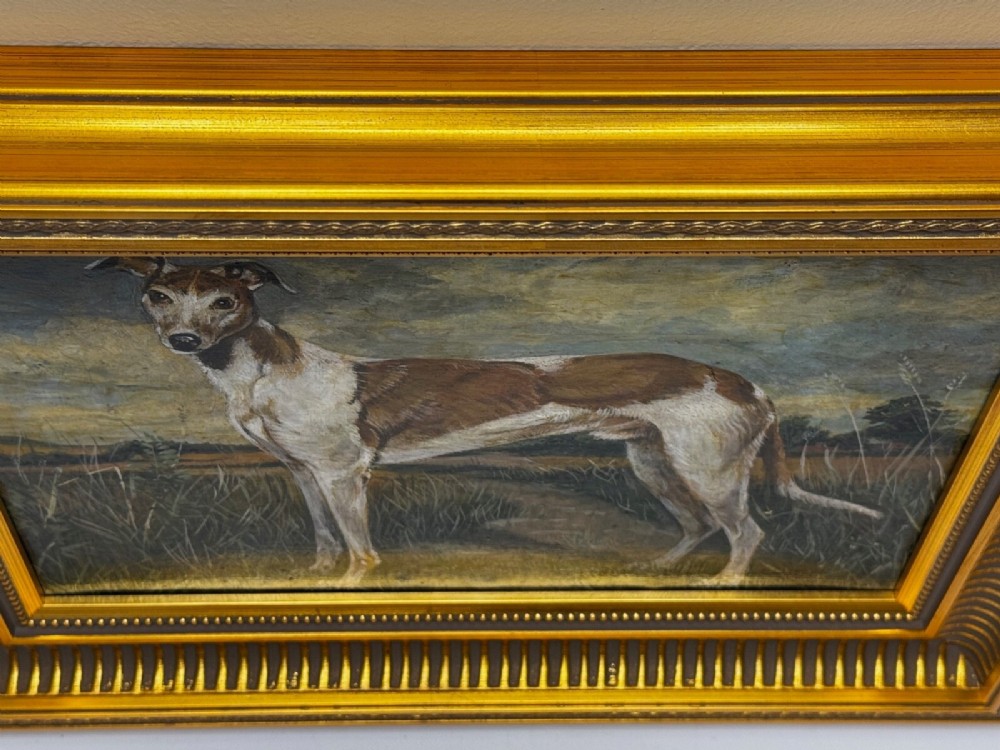 An antique Edwardian oil painting depicting a tan and white lurcher dog in a landscape, set within an ornate gilded frame. View III