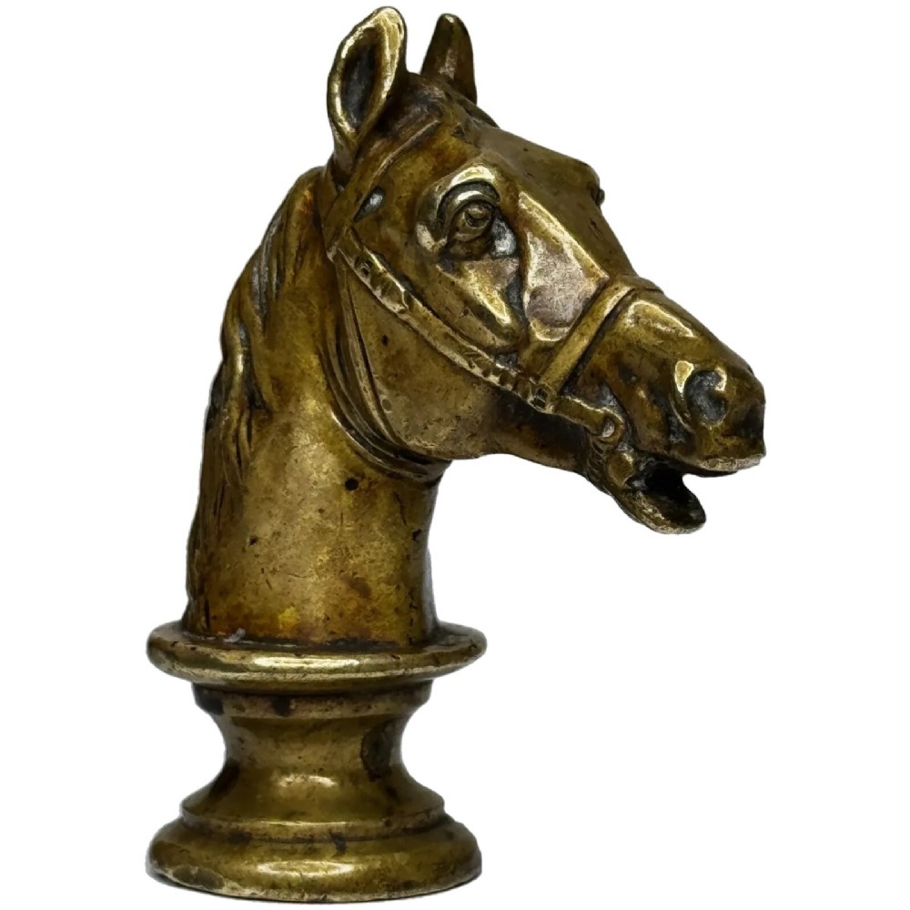 A cast brass Georgian desk seal sculpted in the shape of a detailed horse head above a rounded pedestal with an engraved intaglio base.
