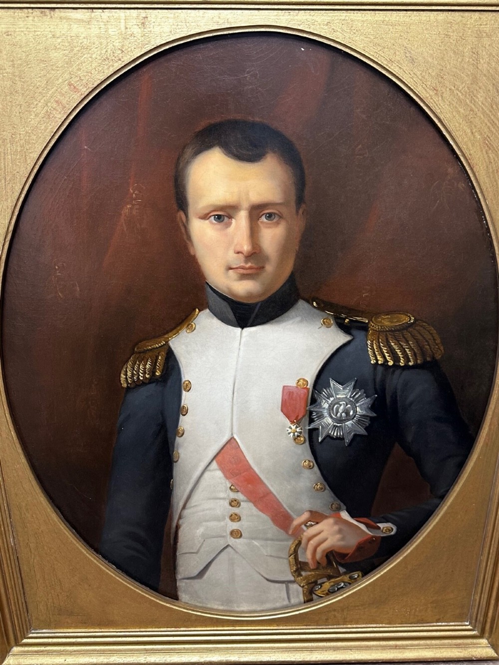 A 19th-century oil painting depicting Napoleon I in a military uniform within an oval spandrel and a rectangular gilded frame. View II