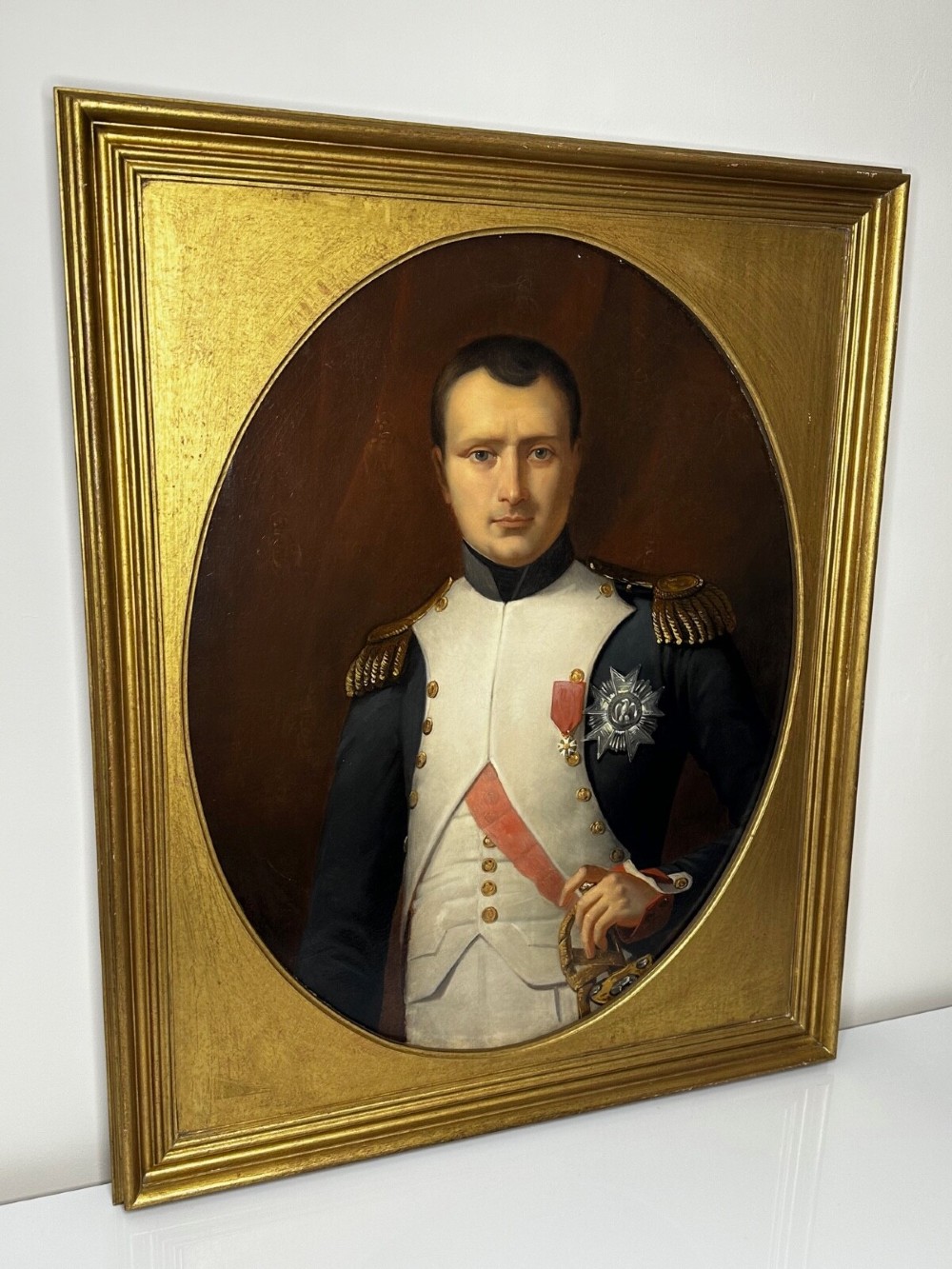 A 19th-century oil painting depicting Napoleon I in a military uniform within an oval spandrel and a rectangular gilded frame. View VIII