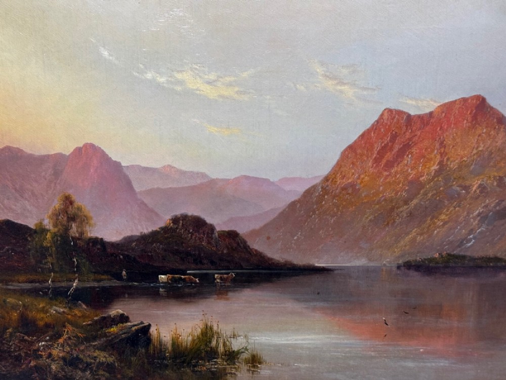 An antique oil painting depicting a lake surrounded by mountains at sunset, enclosed within a carved gold frame. View XV