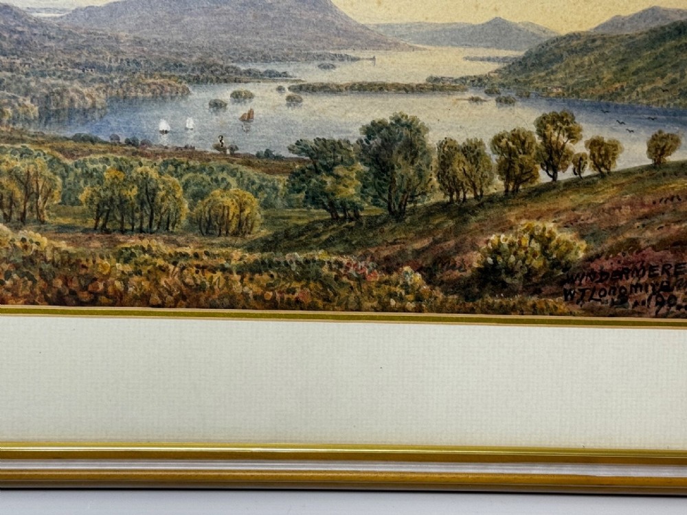 An antique Edwardian watercolour painting depicting Lake Windermere with distant hills, trees, and small boats, framed in gilt with a cream mount. View IV