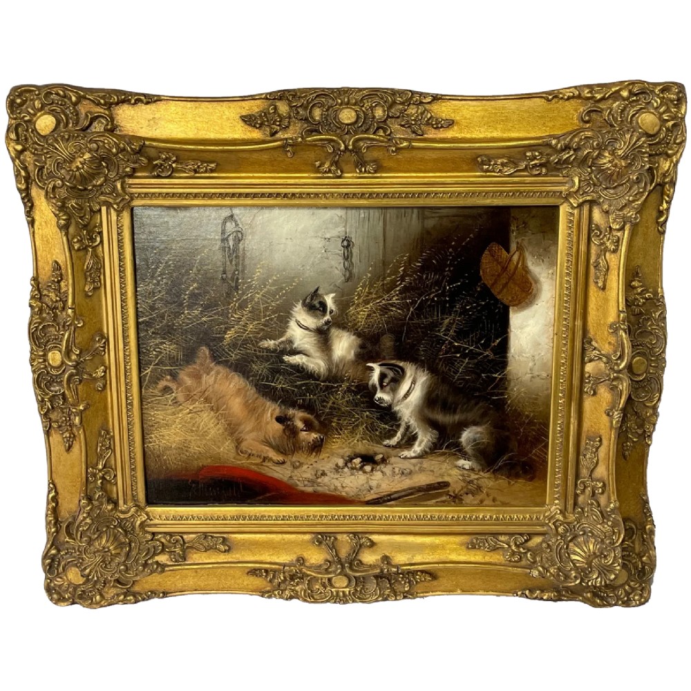 A 19th-century oil painting depicting three working terriers inside a straw-lined barn, presented in an ornate giltwood frame with detailed corner embellishments.