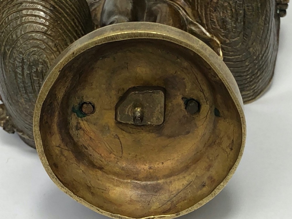 A patinated bronze sculpture depicting a young girl carrying two large woven baskets on a rounded base. View IV