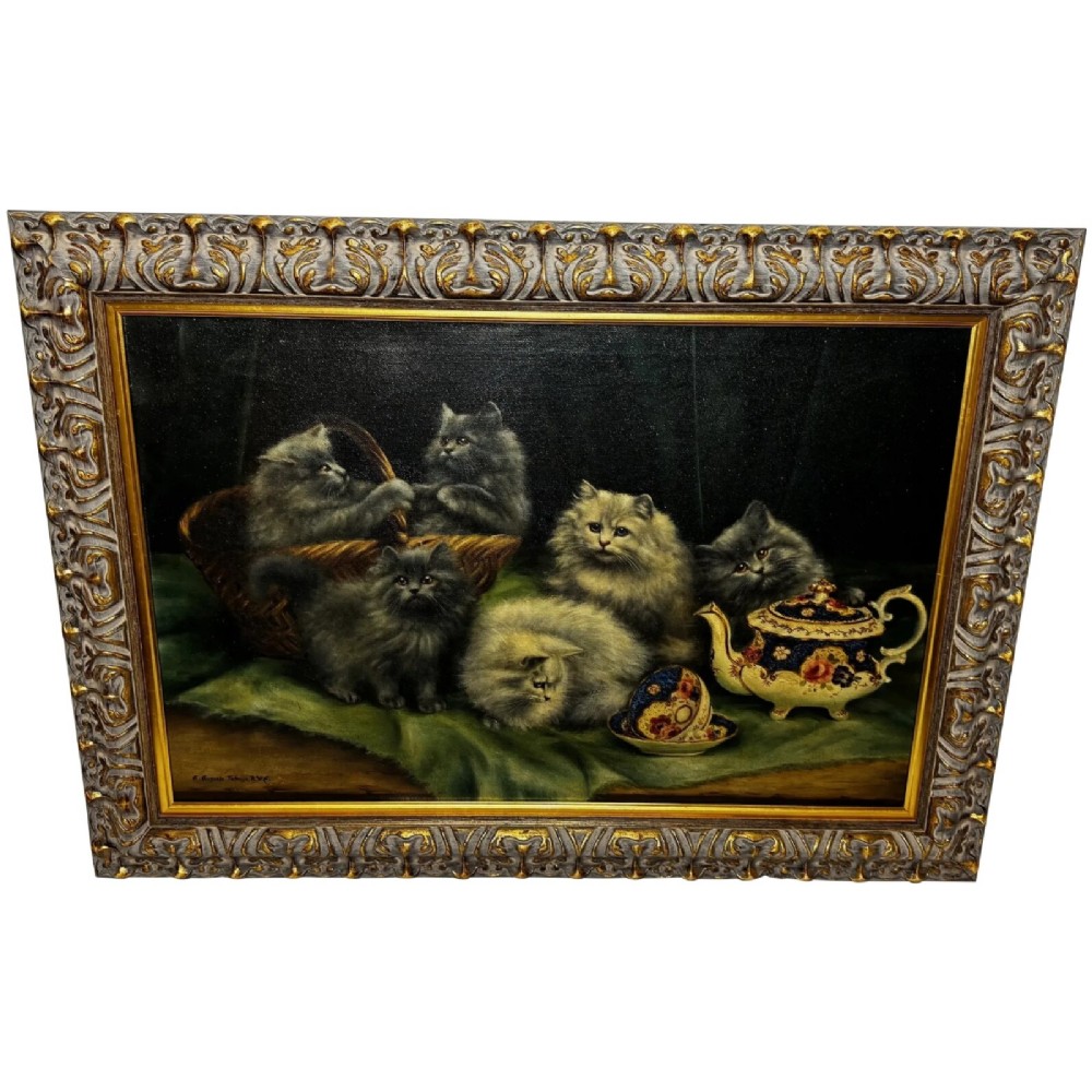 An antique framed oil painting depicting five grey and cream Persian kittens positioned around a wicker basket and a floral porcelain teapot.
