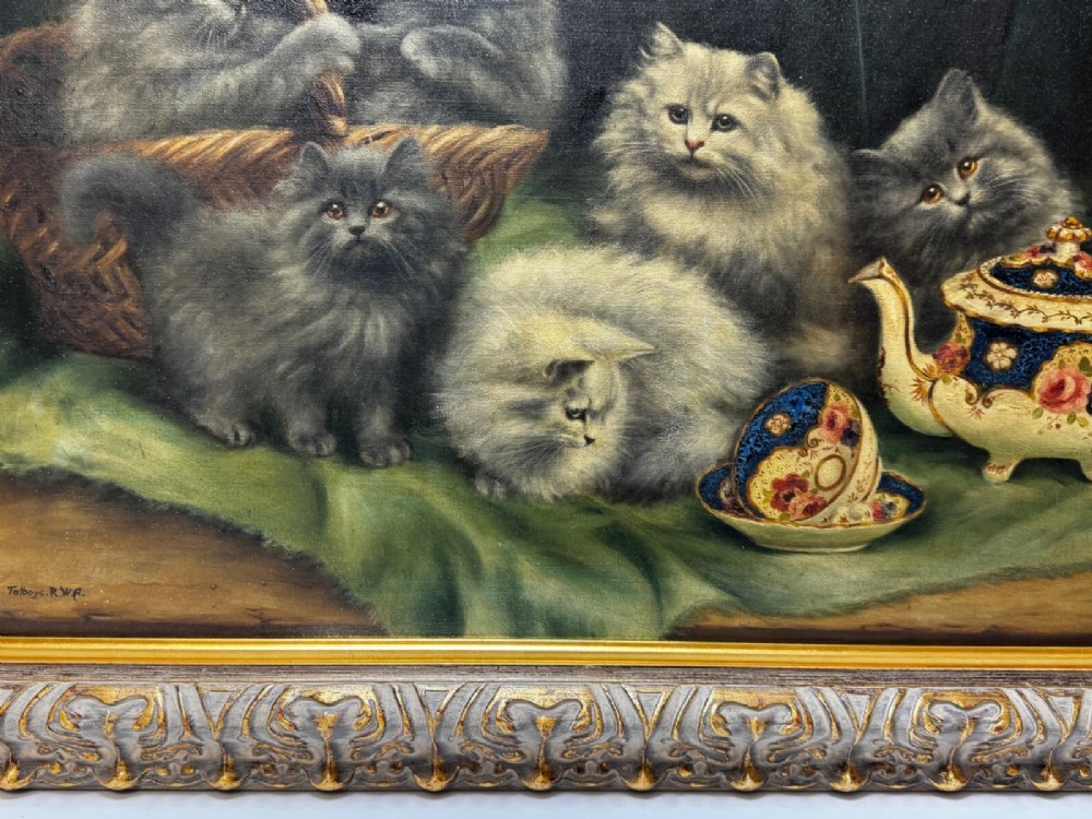 An antique framed oil painting depicting five grey and cream Persian kittens positioned around a wicker basket and a floral porcelain teapot. View III
