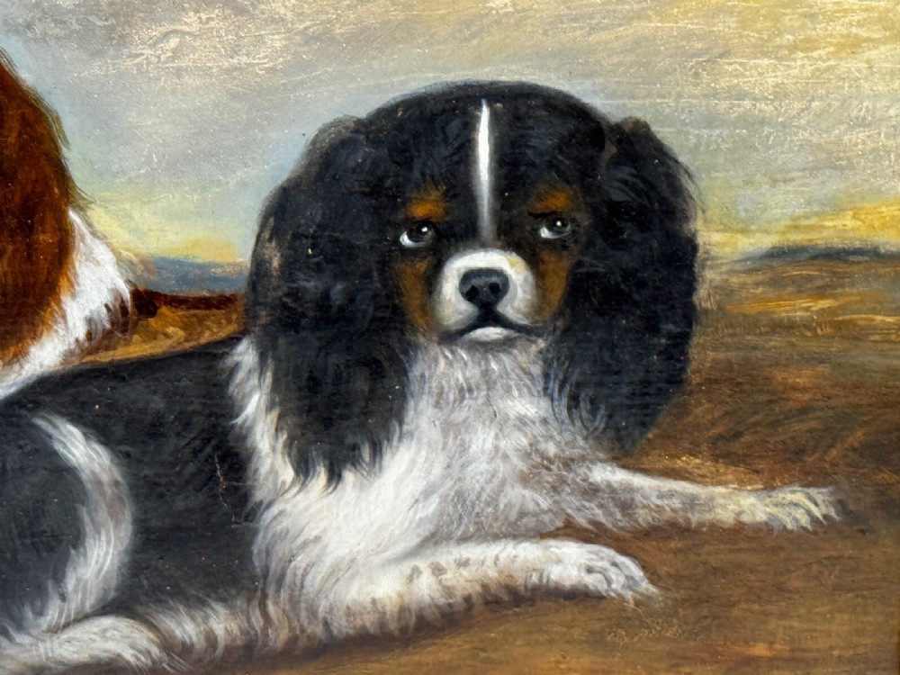 A nineteenth-century framed oil painting depicting a Blenheim spaniel and a tricolour spaniel seated outdoors, enclosed within an ornate gold giltwood frame. View XII