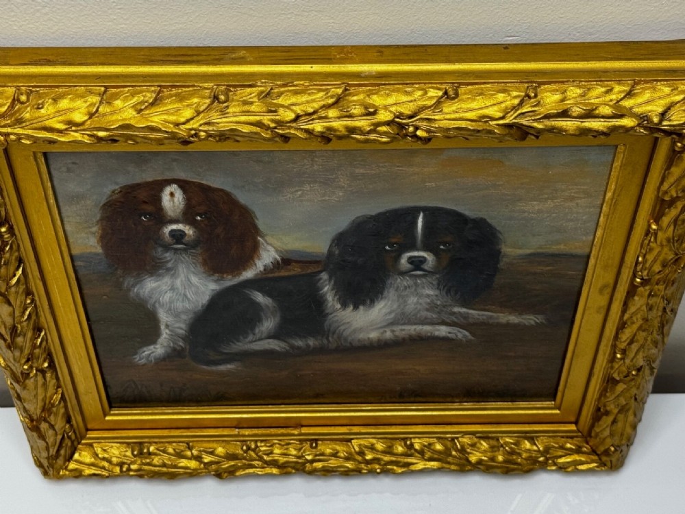 A nineteenth-century framed oil painting depicting a Blenheim spaniel and a tricolour spaniel seated outdoors, enclosed within an ornate gold giltwood frame. View XV