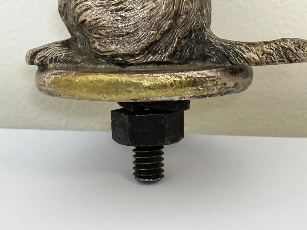 A cast bronze car mascot depicting a Scottish Terrier sitting in a begging pose mounted on a small circular base with a threaded bolt. View V