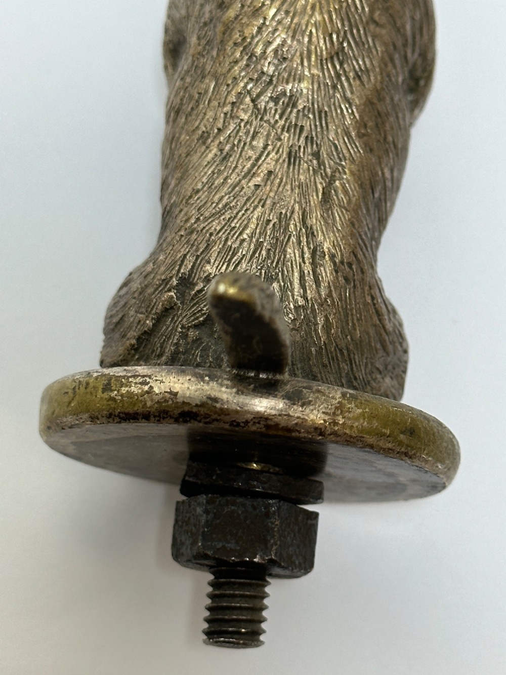 A cast bronze car mascot depicting a Scottish Terrier sitting in a begging pose mounted on a small circular base with a threaded bolt. View VII