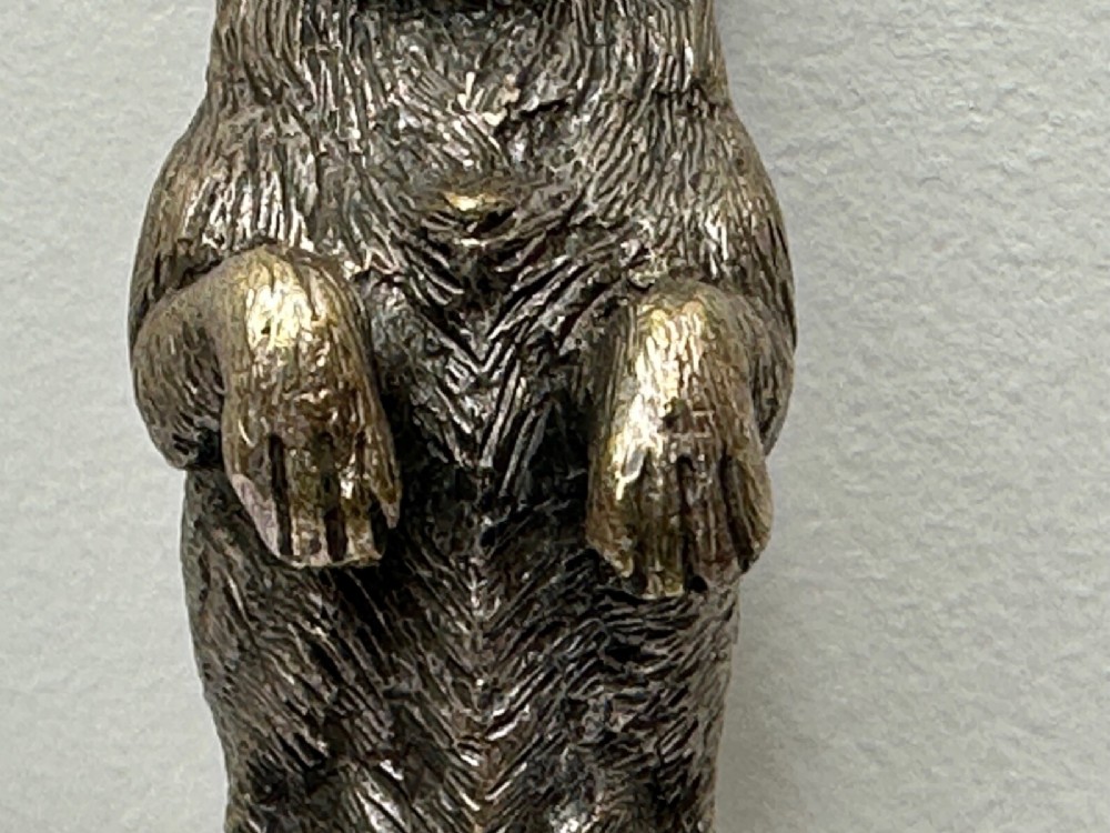 A cast bronze car mascot depicting a Scottish Terrier sitting in a begging pose mounted on a small circular base with a threaded bolt. View XI