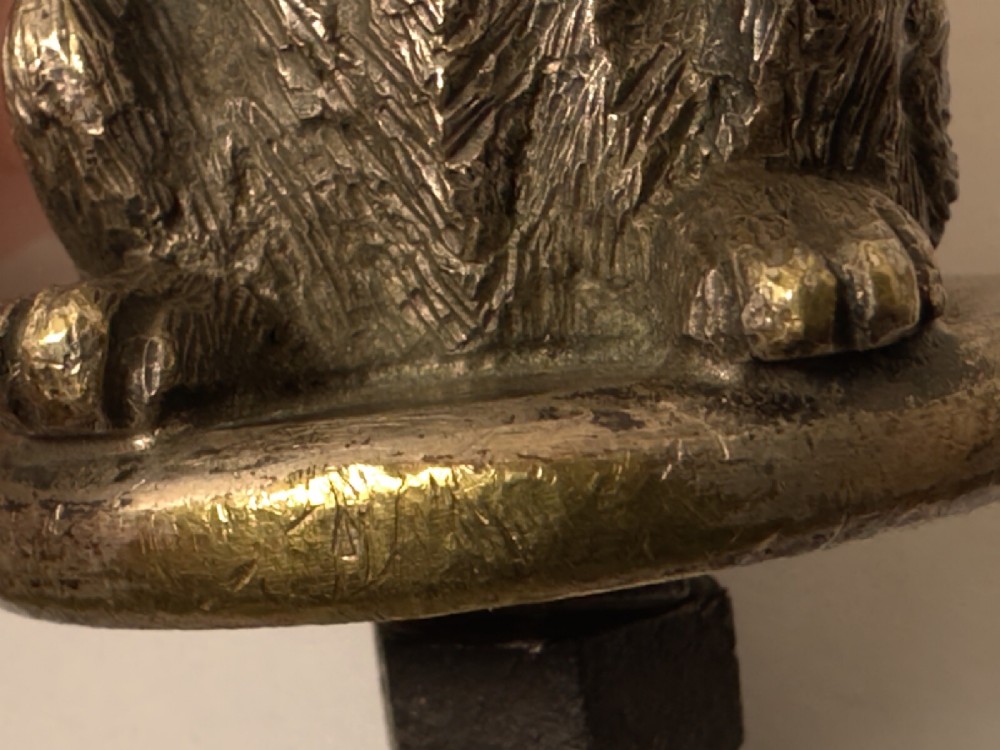 A cast bronze car mascot depicting a Scottish Terrier sitting in a begging pose mounted on a small circular base with a threaded bolt. View XII