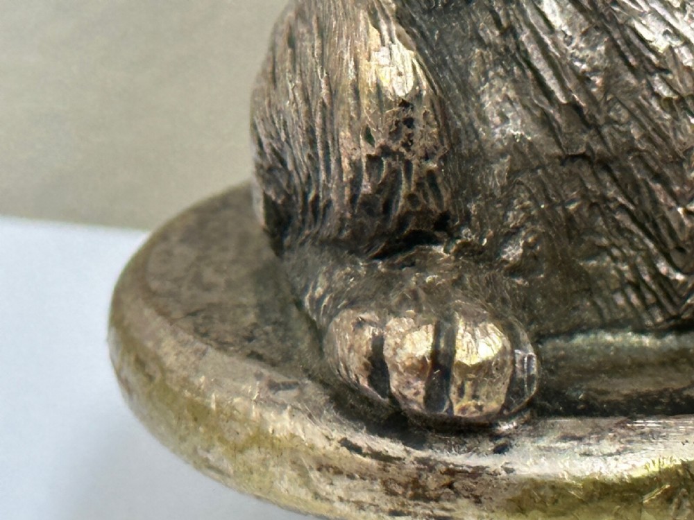 A cast bronze car mascot depicting a Scottish Terrier sitting in a begging pose mounted on a small circular base with a threaded bolt. View XIV