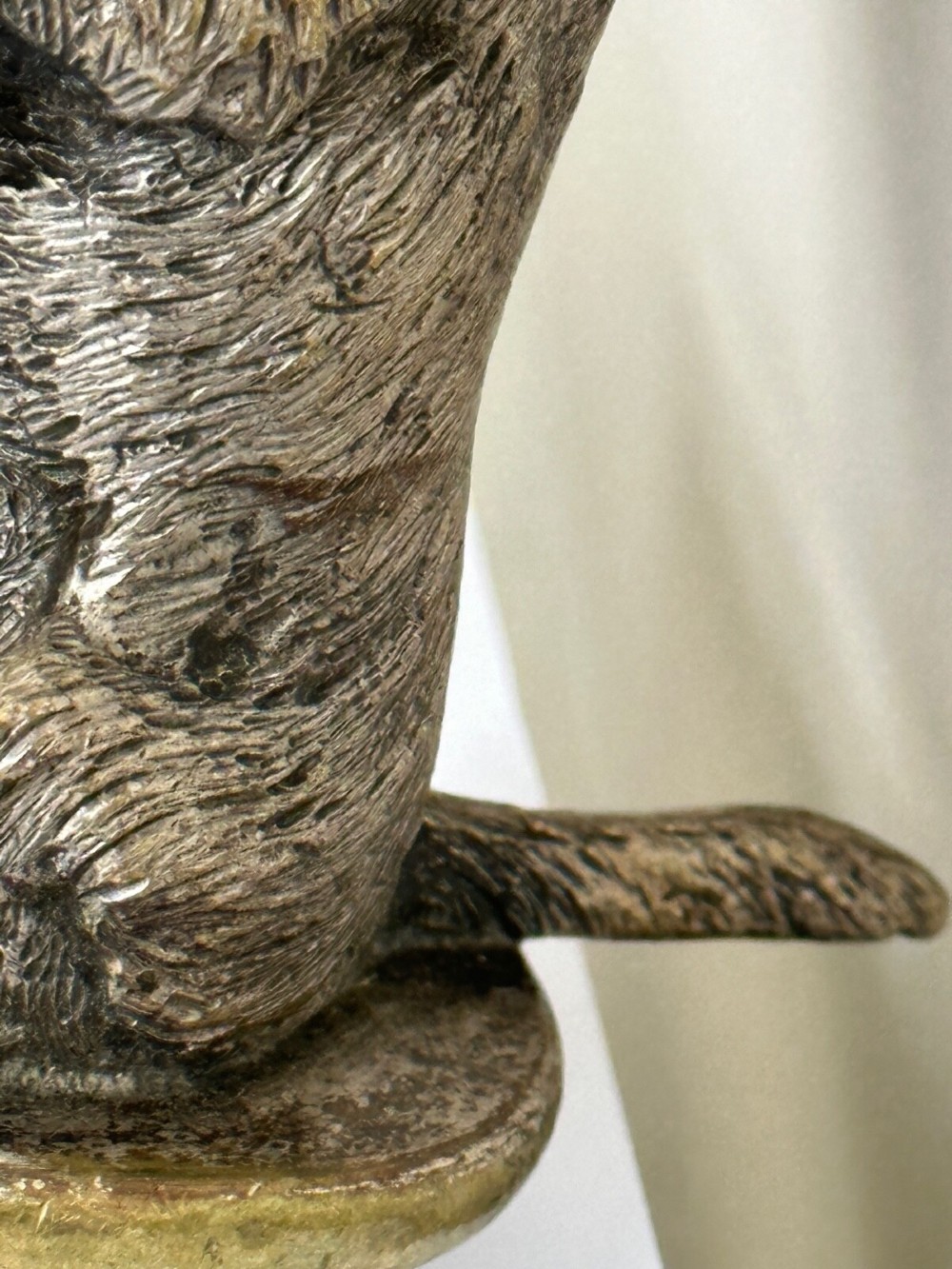 A cast bronze car mascot depicting a Scottish Terrier sitting in a begging pose mounted on a small circular base with a threaded bolt. View XV