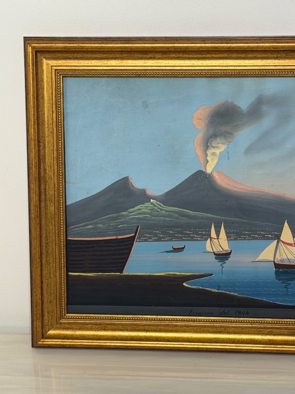 A framed 19th-century gouache painting depicting the eruption of Mount Vesuvius over the Bay of Naples with sailboats in the foreground. View III
