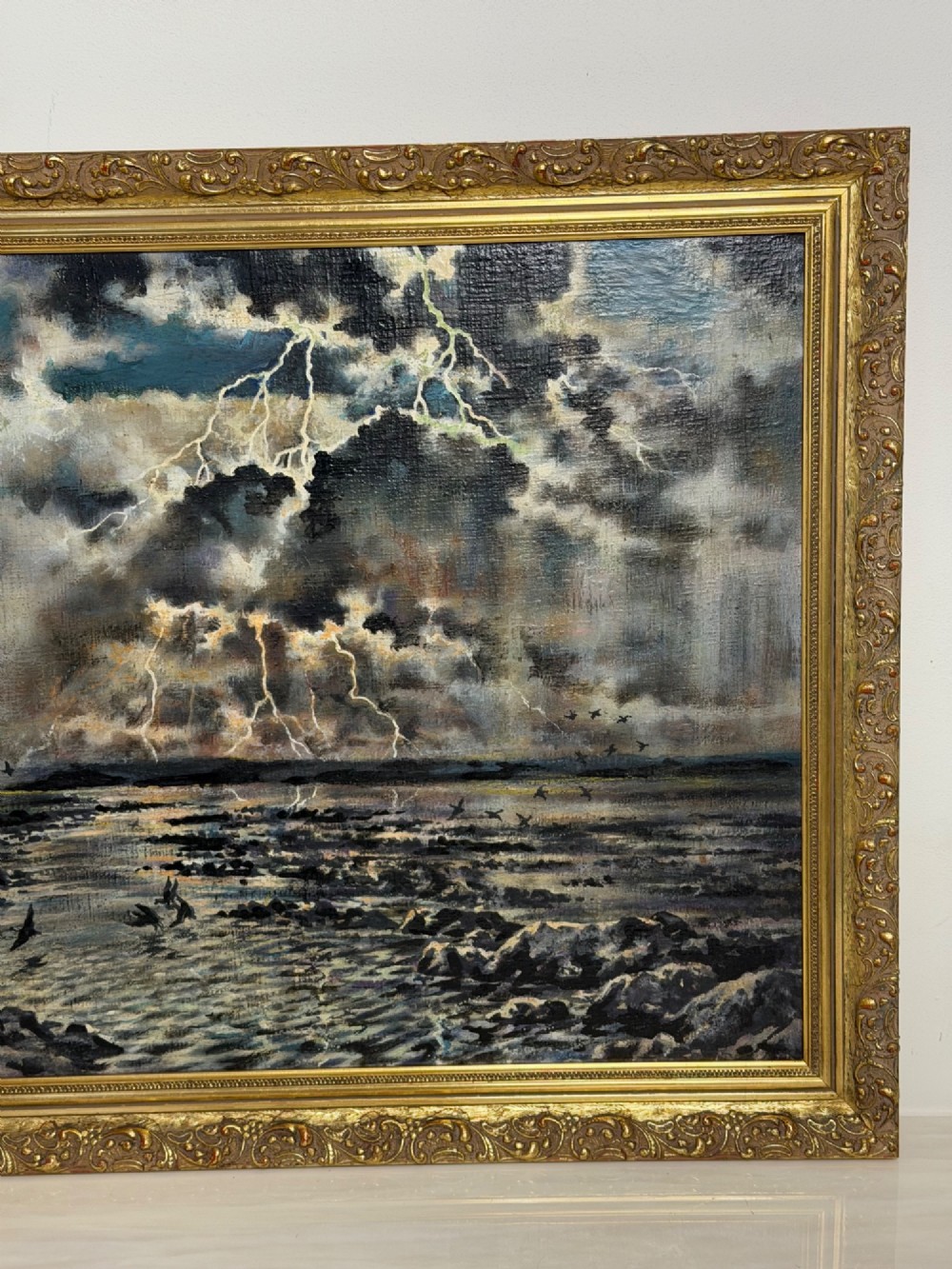 A framed oil painting depicting a lightning storm over a rocky coastal bay with birds flying near the water surface. View II