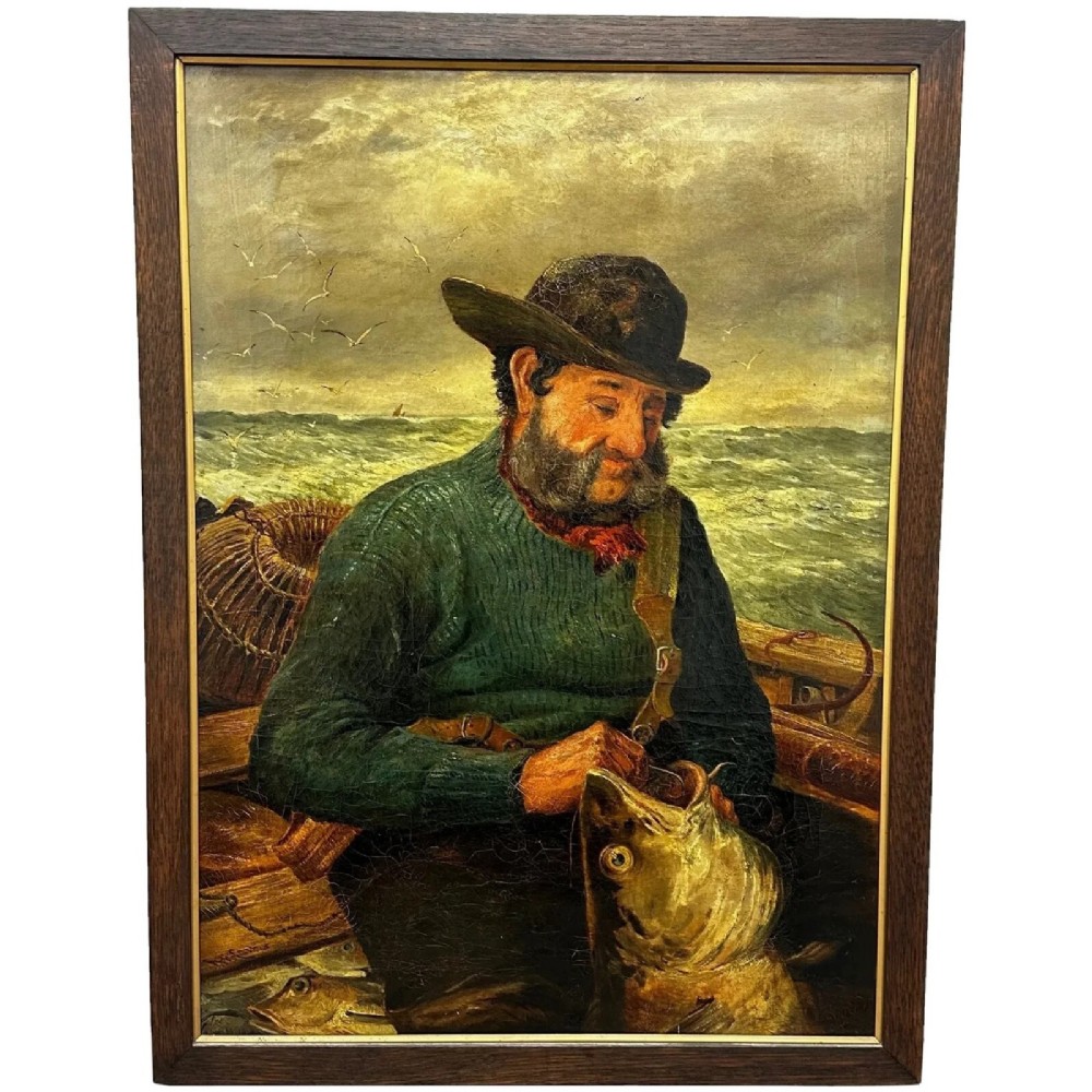 An antique oil painting depicting a bearded fisherman in a green knitted jumper sitting in a boat with his catch, encased in a dark wooden frame.
