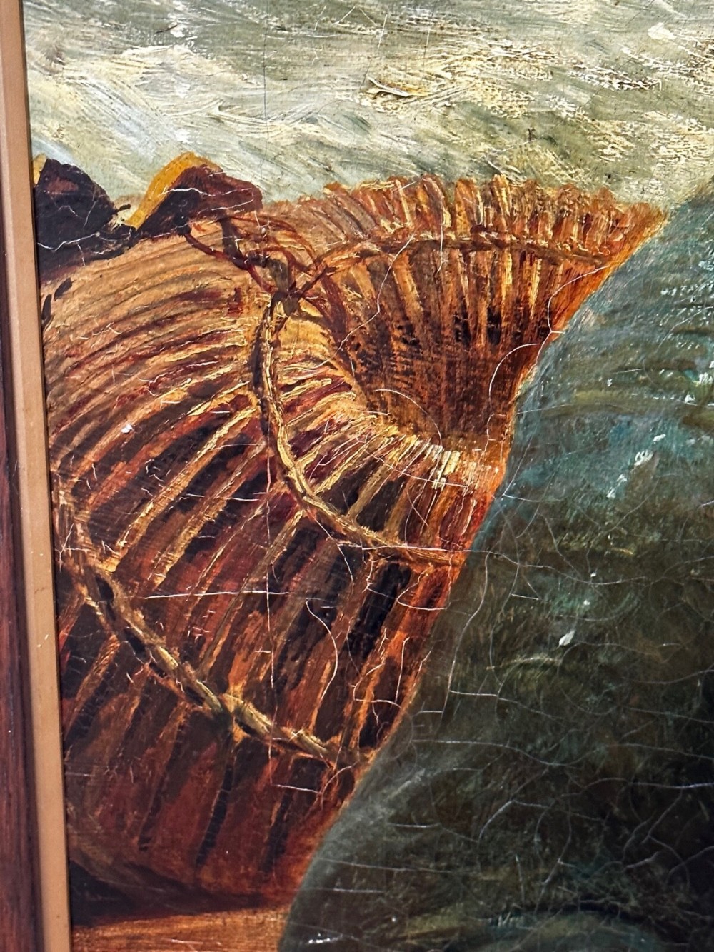 An antique oil painting depicting a bearded fisherman in a green knitted jumper sitting in a boat with his catch, encased in a dark wooden frame. View X