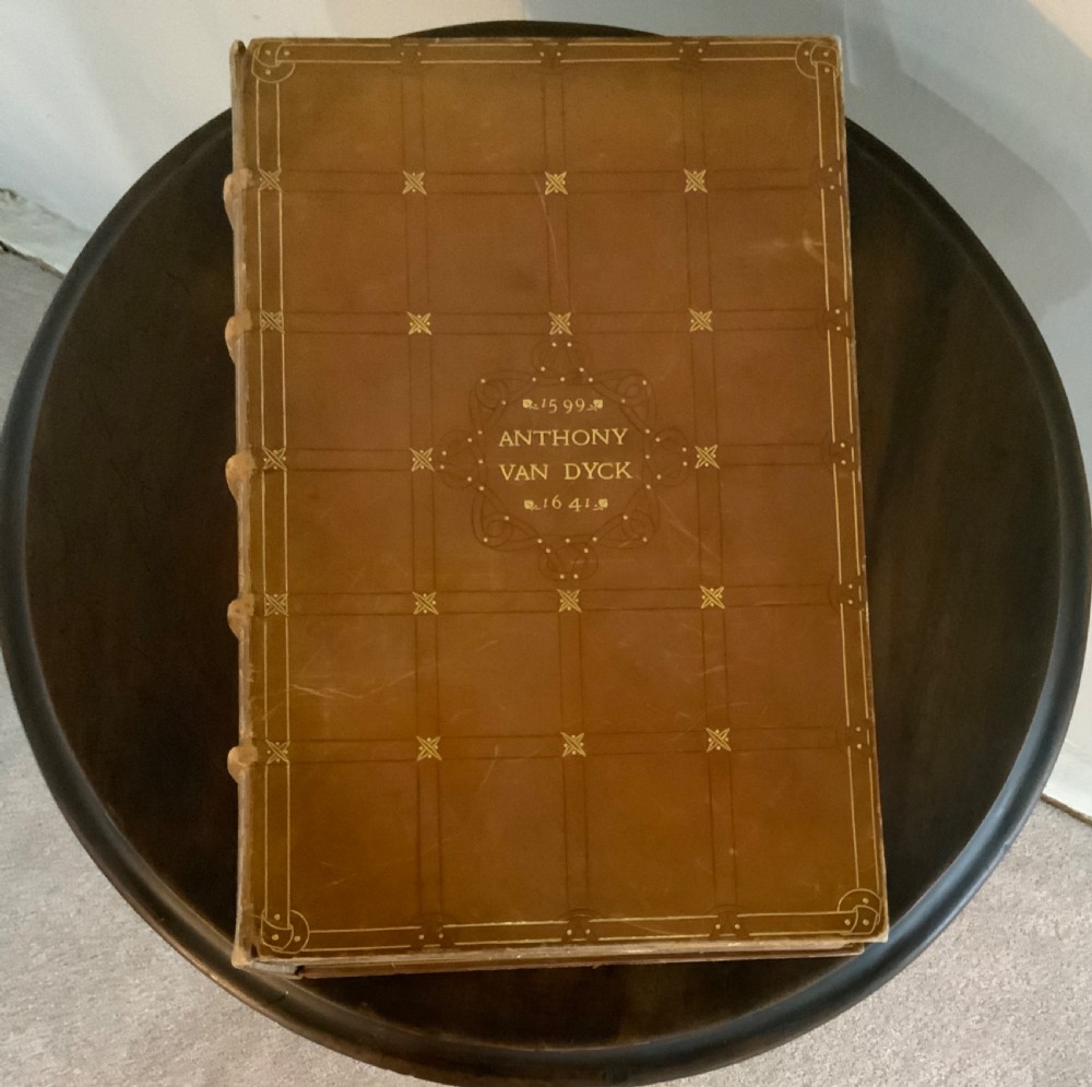 A large tan leather-bound antique book featuring ornate gold gilt tooling on the spine and front cover. View III
