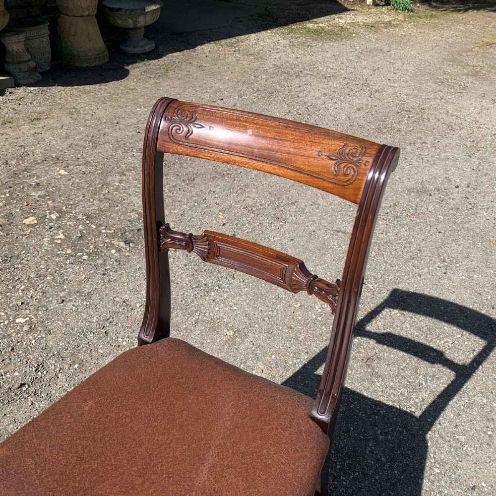A set of four Regency mahogany dining chairs with carved bar backs, dark brown upholstered seats, and turned front legs. View IV