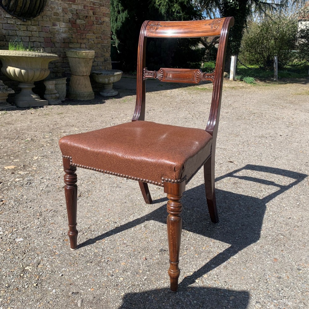 A set of four Regency mahogany dining chairs with carved bar backs, dark brown upholstered seats, and turned front legs. View V