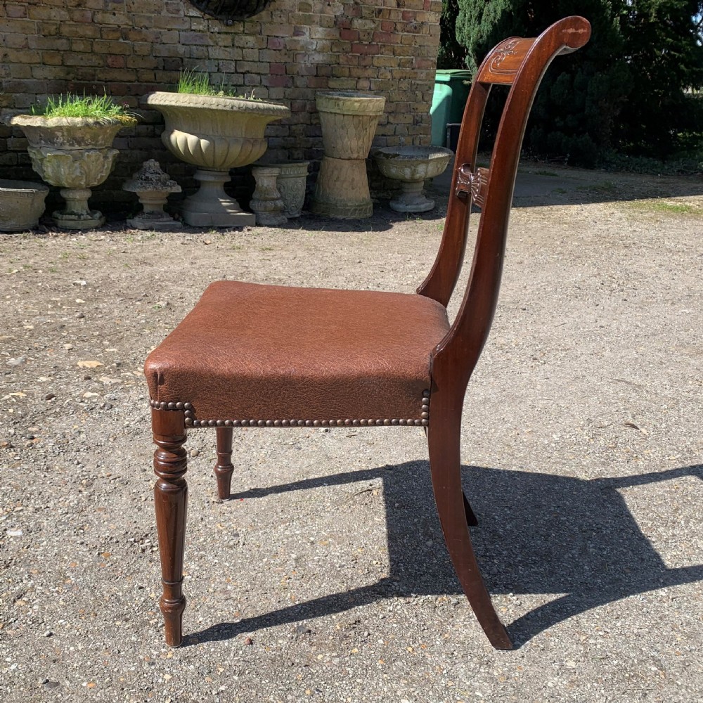 A set of four Regency mahogany dining chairs with carved bar backs, dark brown upholstered seats, and turned front legs. View VI