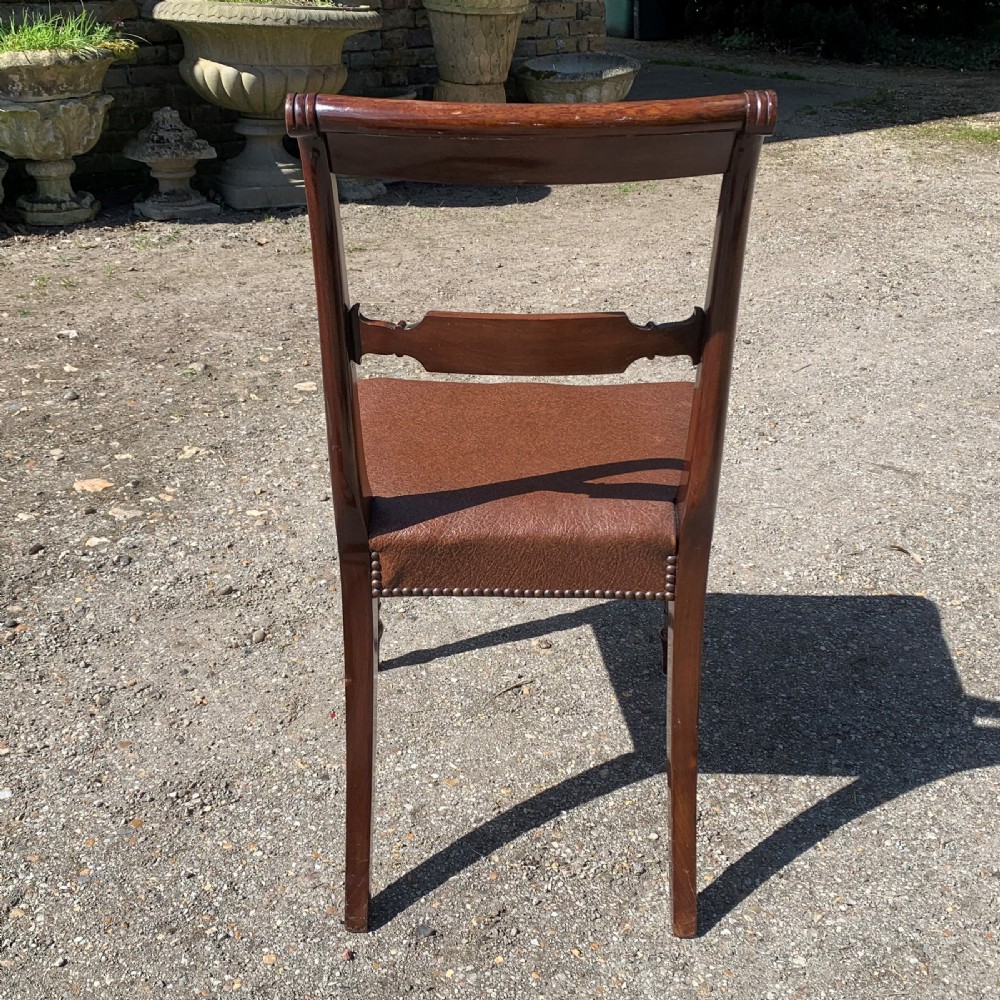 A set of four Regency mahogany dining chairs with carved bar backs, dark brown upholstered seats, and turned front legs. View VII