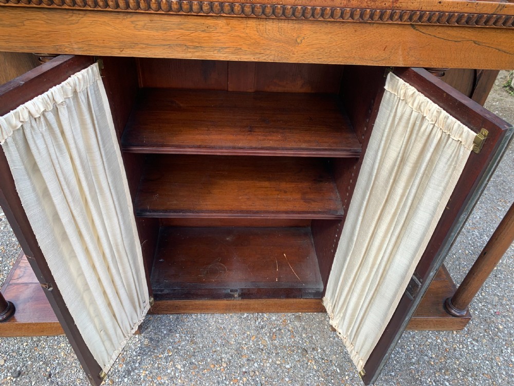 A Regency rosewood breakfront chiffonier cabinet featuring an upper mirrored shelf unit supported by turned columns over central mesh-panelled doors lined with fabric. View IV