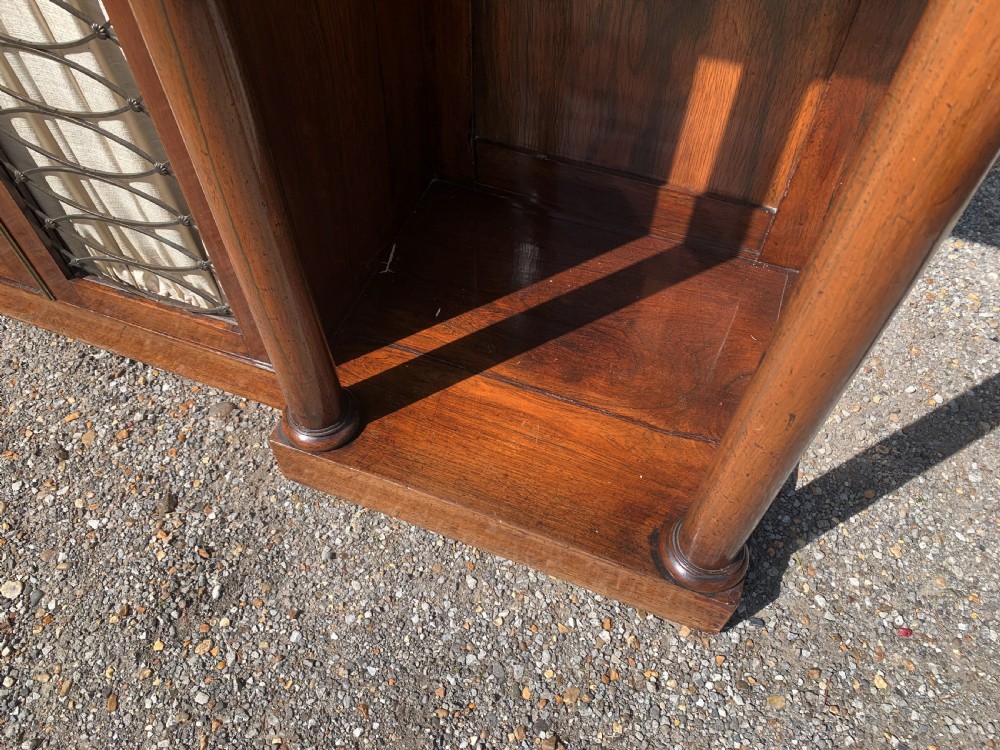 A Regency rosewood breakfront chiffonier cabinet featuring an upper mirrored shelf unit supported by turned columns over central mesh-panelled doors lined with fabric. View VI