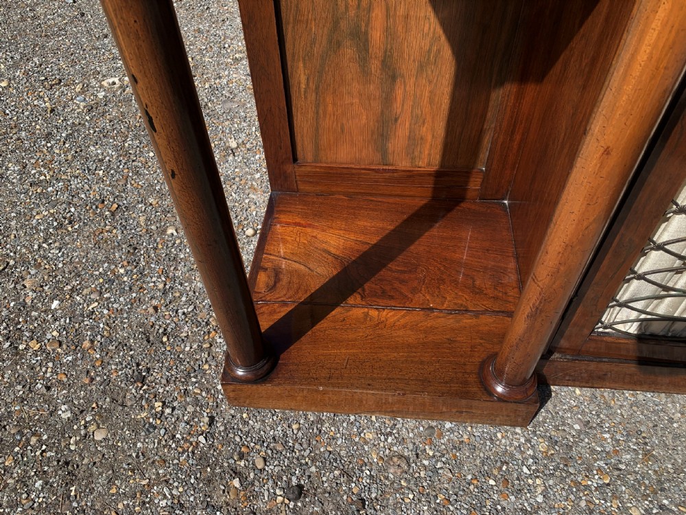 A Regency rosewood breakfront chiffonier cabinet featuring an upper mirrored shelf unit supported by turned columns over central mesh-panelled doors lined with fabric. View VII