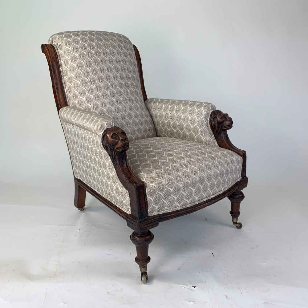 An antique high-back armchair featuring carved lion head armrests, turned wooden legs on castors, and patterned fabric upholstery. View II