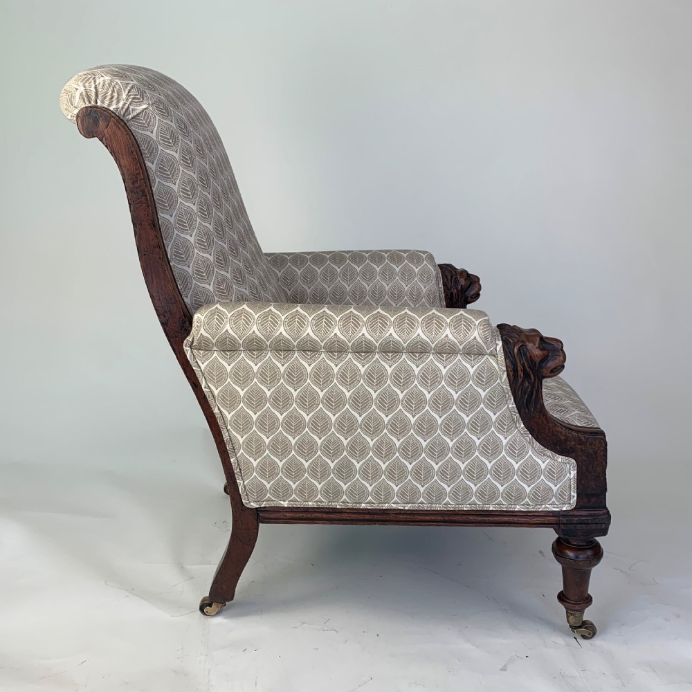 An antique high-back armchair featuring carved lion head armrests, turned wooden legs on castors, and patterned fabric upholstery. View IV