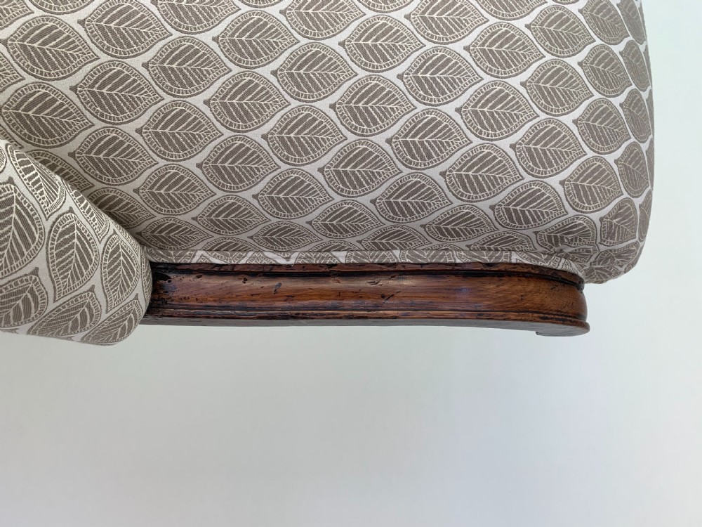 An antique high-back armchair featuring carved lion head armrests, turned wooden legs on castors, and patterned fabric upholstery. View XIII