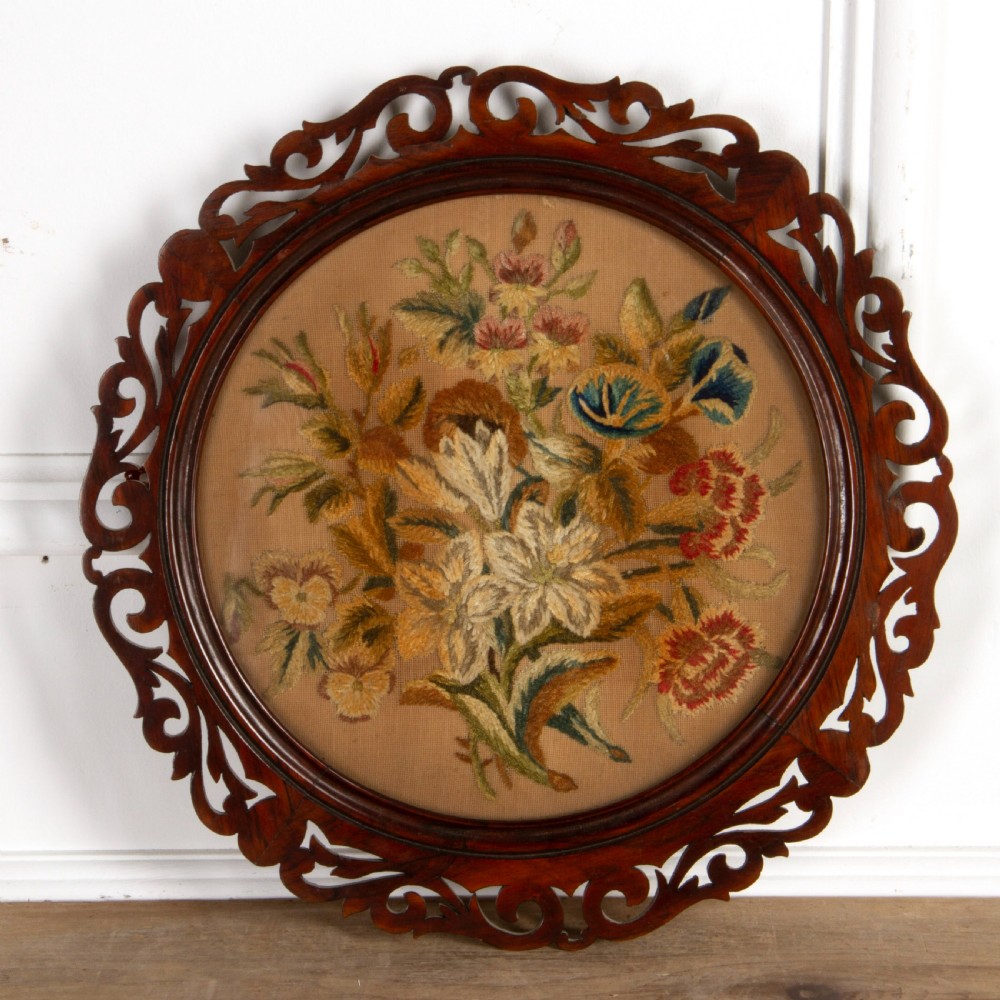 A pair of circular antique floral needlework panels housed within dark mahogany pierced openwork frames. View II