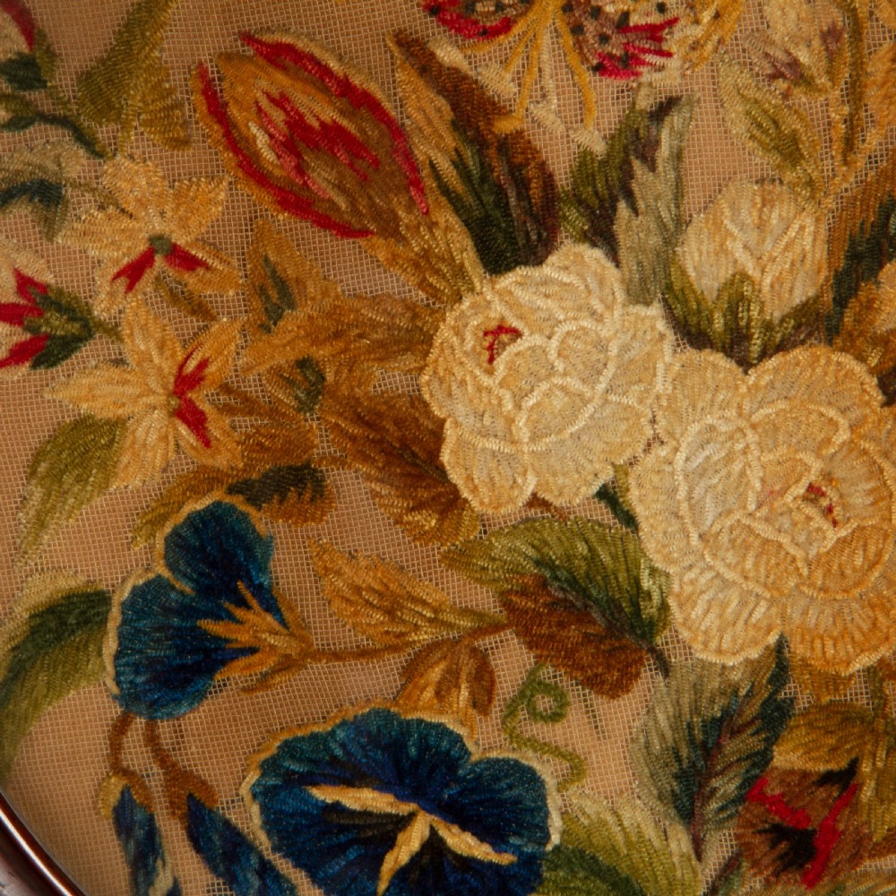 A pair of circular antique floral needlework panels housed within dark mahogany pierced openwork frames. View V