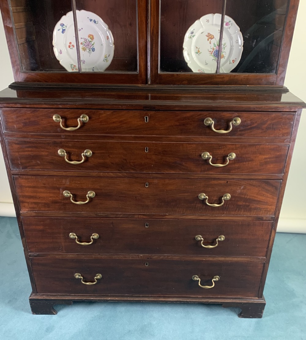 A dark mahogany Georgian secretaire bookcase featuring two upper glazed doors with Gothic astragal arches above a chest of five drawers with brass handles. View IV