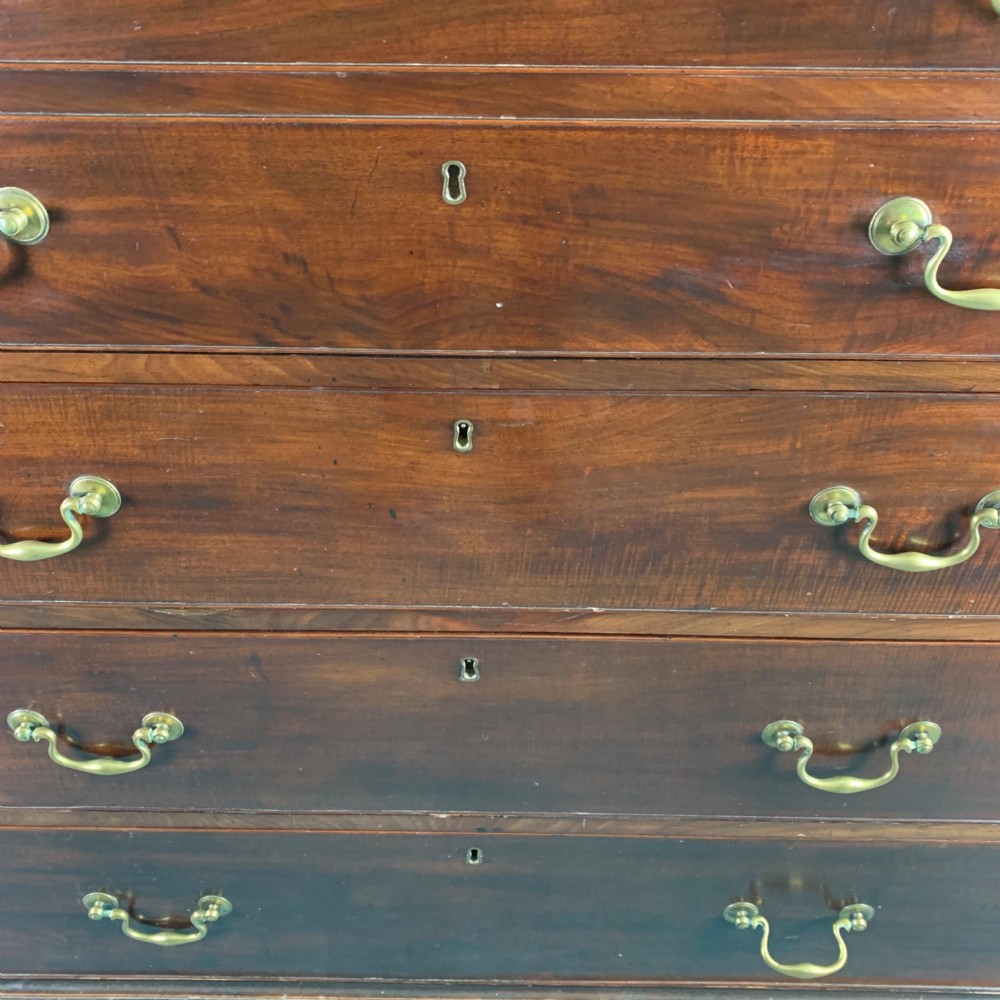 A dark mahogany Georgian secretaire bookcase featuring two upper glazed doors with Gothic astragal arches above a chest of five drawers with brass handles. View V