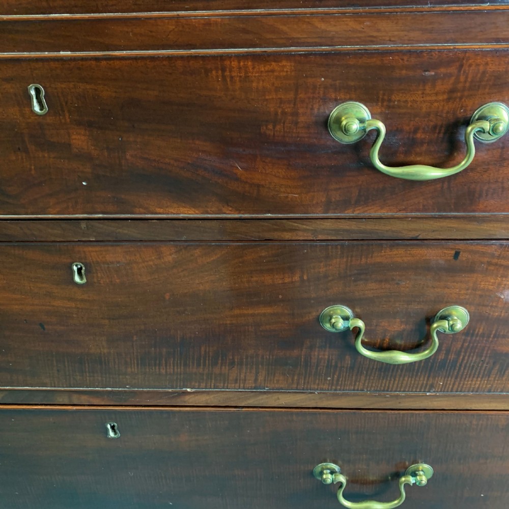 A dark mahogany Georgian secretaire bookcase featuring two upper glazed doors with Gothic astragal arches above a chest of five drawers with brass handles. View VI