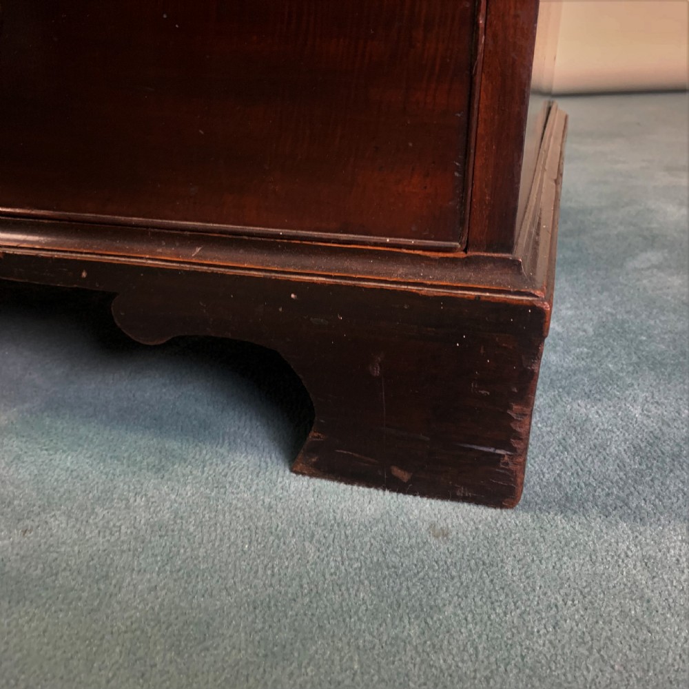 A dark mahogany Georgian secretaire bookcase featuring two upper glazed doors with Gothic astragal arches above a chest of five drawers with brass handles. View VII