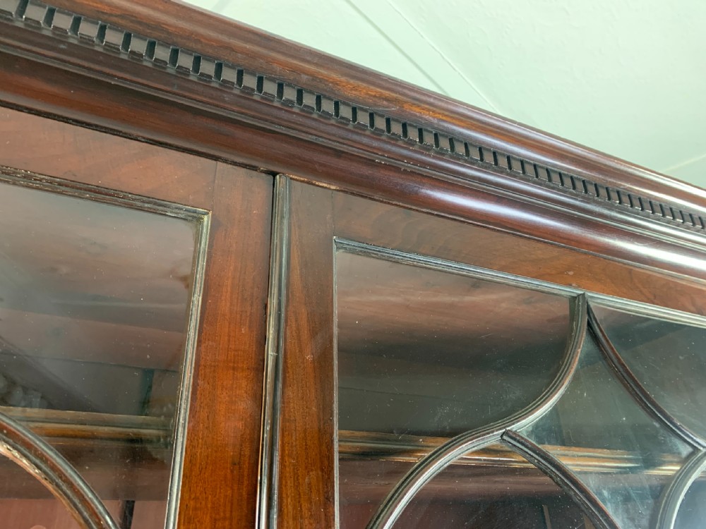 A dark mahogany Georgian secretaire bookcase featuring two upper glazed doors with Gothic astragal arches above a chest of five drawers with brass handles. View VIII