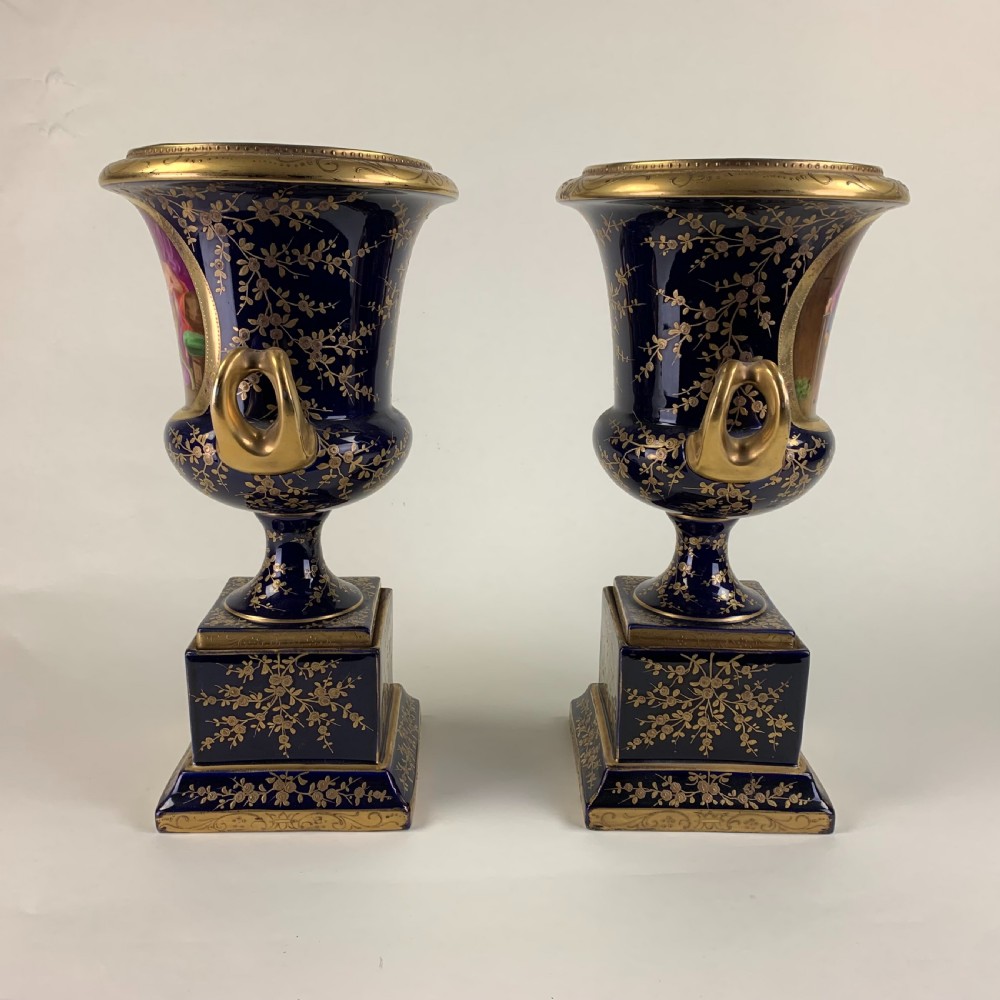 A pair of cobalt blue and gold Vienna porcelain urns with hand-painted classical scenes on square plinths. View II