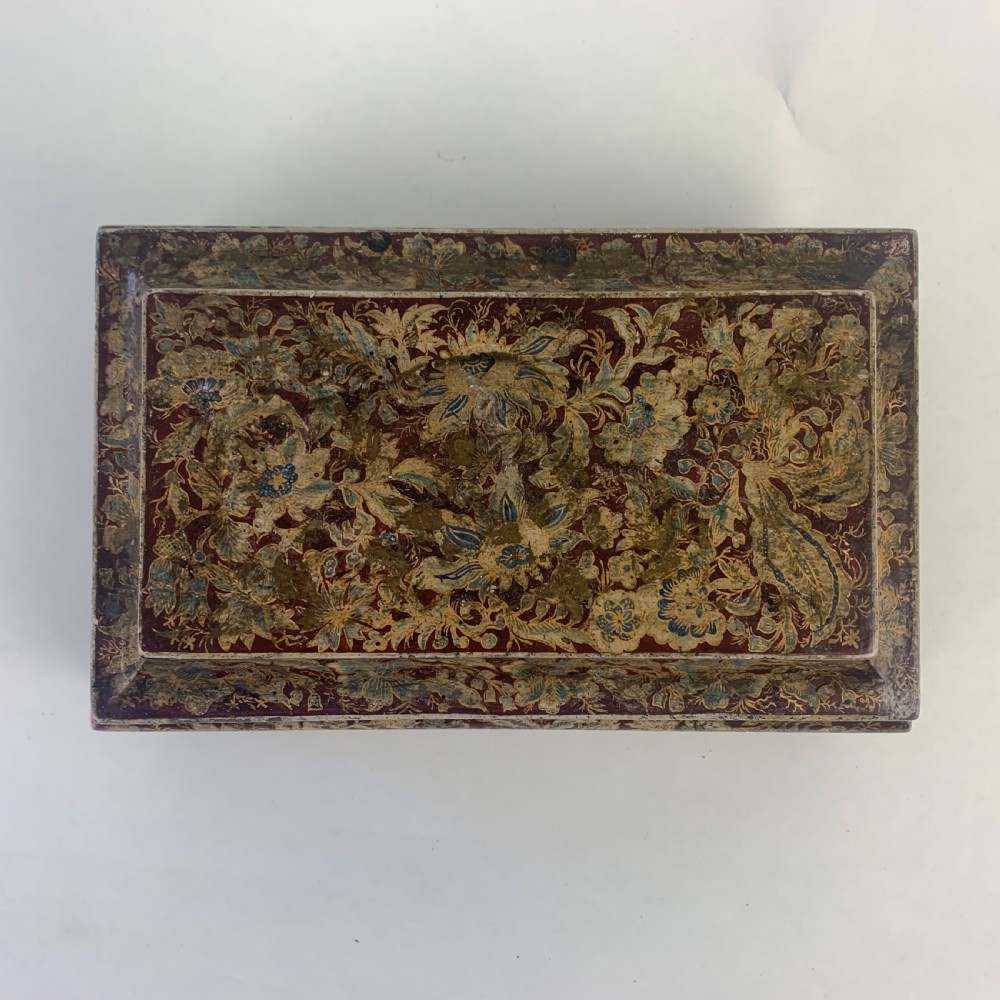 A rectangular early 19th-century Regency wooden games box, hand-painted with intricate botanical patterns in burgundy, gold, and green, featuring a sarcophagus-style lid and small ball feet. View IV